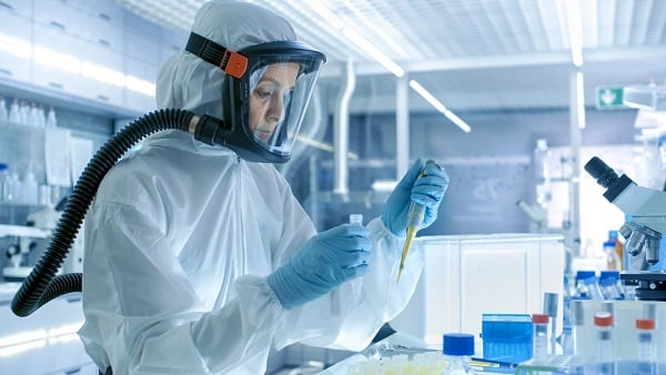 Female scientist with vile and PPE for DTRA Funding Guide