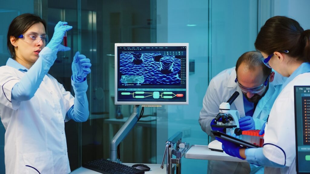 Senior chemist analysing blood sample while working overtime in chemistry equipped laboratory.